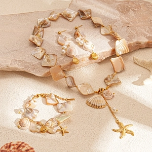 Detail of seashell and starfish necklace set on stone surface for beach vacation look
