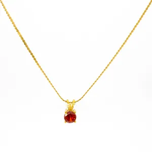 Macro detail of 18K gold plated chain with round red cubic zirconia pendant in four-prong setting