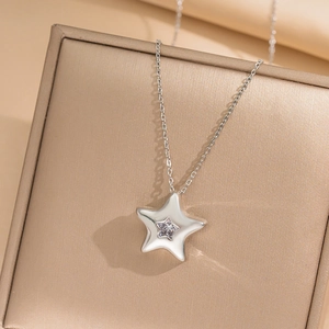 Minimalist silver star necklace with a clear gemstone pendant on a jewelry stand
