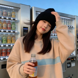 Street style view of a beige sweatshirt paired with a thick black knit beanie hat