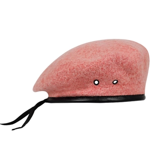 Detailed view of pink wool beret with black leather trim and decorative ribbons