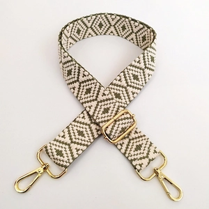 Detail of adjustable geometric diamond jacquard bag strap with gold metal hardware