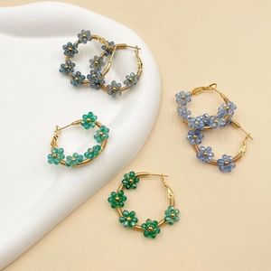 Detailed macro view of handmade crystal flower beaded gold hoop earrings in three colors