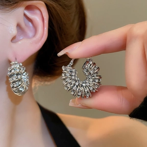 Close-up of silver-tone spiral earrings featuring shimmering pavé diamond-like crystals