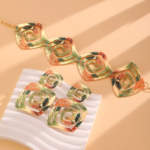 Détail d'un ensemble de bijoux géométriques dorés avec des motifs de feuilles tropicales