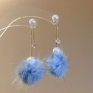 Detail of gold plated drop earrings with white pearl, zircon and blue pom pom pendant