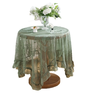 Elegant green lace tablecloth with ruffle edge and floral cutout pattern on a round table