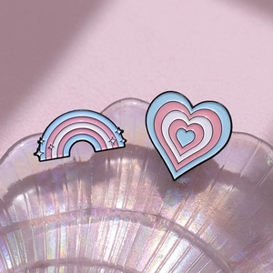 Pink heart and rainbow enamel pins set in blue and white on iridescent shell surface