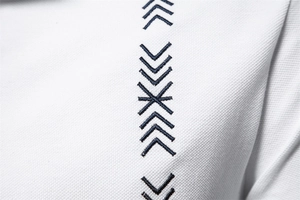 Macro view of white pique cotton fabric with dark blue geometric arrow embroidery detail