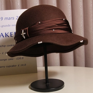 Detail of a brown wool cloche hat with satin ribbon and decorative pearl embellishments