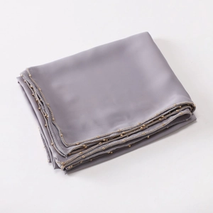 Detail view of smooth grey satin scarf featuring elegant gold bead chain trimming on the edge