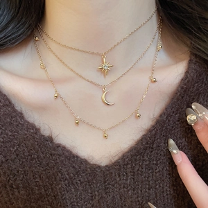 Close-up of triple-layered gold star and moon pendant necklace with rhinestone details