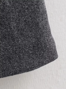 Detail showing the dark grey wool fabric texture and stitching on long coat