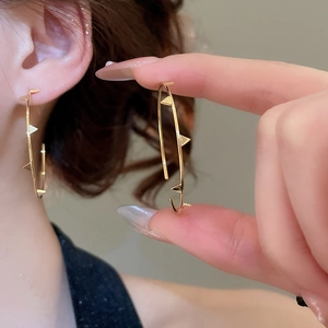 Detailed view of gold hoop earrings featuring modern pyramid stud accents for women