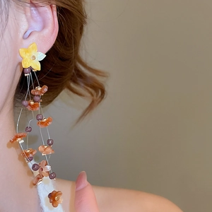 Detail of floral tassel earrings with yellow resin flowers and colorful beads on model
