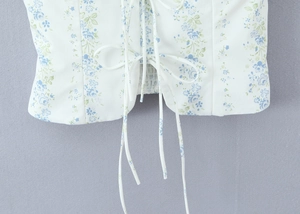Detail of floral print top featuring adjustable front drawstring tie and blue botanical patterns