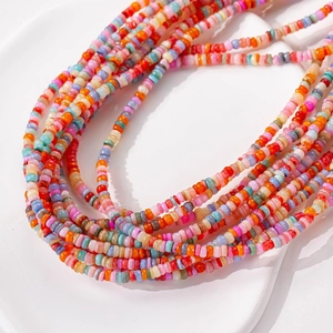 Collane e braccialetti di perle colorate da 3mm impilati su un piatto bianco