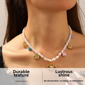 Détail du collier de perles avec pendentifs dorés, motifs soleil et turquoise