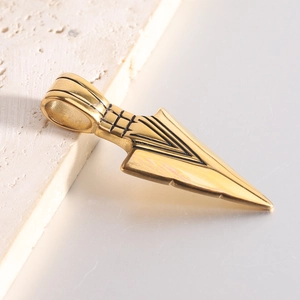 Macro shot of a golden stainless steel arrow pendant with intricate black grid details