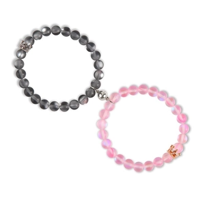 Close-up of magnetic matching couple bracelets with grey and pink beads and crown charms