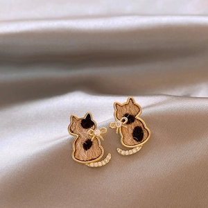 Macro shot of gold-plated cat earrings with leopard print fabric and zircon details