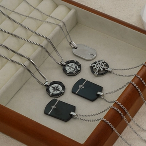 Stainless steel star and compass pendant necklaces on a wooden tray with linen background