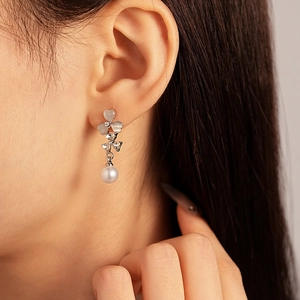 Boucles d'oreilles fleur œil de chat et perle blanche portées par un mannequin
