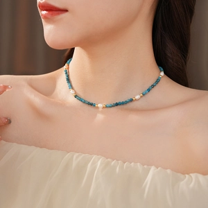 Detail of beaded necklace with blue natural stones, pearls and gold beads on a model
