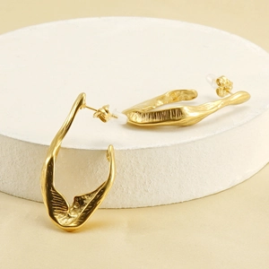 Golden 18K stainless steel irregular lava texture earrings on a white stone pedestal