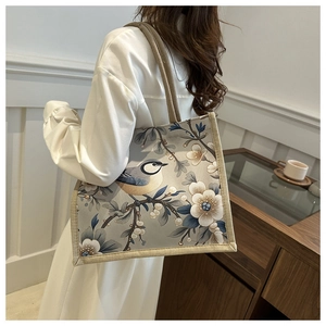 Detail of floral and bird print on large tote bag with woven shoulder strap