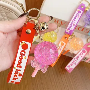 Glow-in-the-dark lollipop keychain with sequins, gold bell and colorful silicone strap