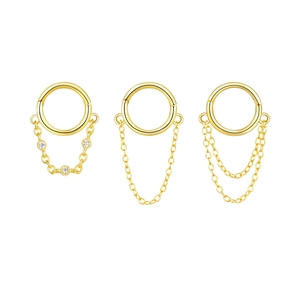 Dettaglio di tre anelli piercing in argento S925 dorato con catenine e pendenti in zircone