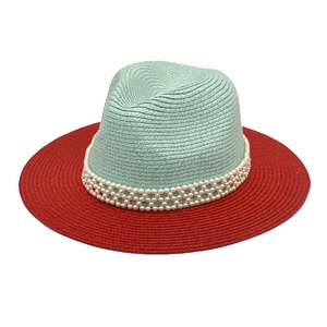 Detail of mint green and red straw hat with triple-layer pearl accents for beach sun protection