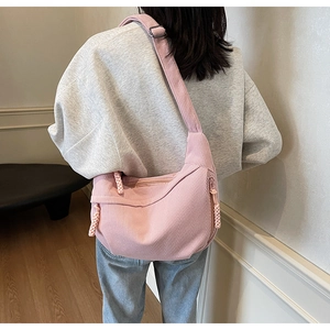 Pink corduroy crossbody dumpling bag with wide adjustable strap and side knot detail