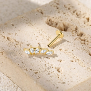 Detail of gold butterfly ear stud with marquise crystals on textured stone surface