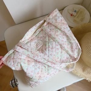 Macro shot of floral quilted cotton tote bag with French label detail and diamond stitching