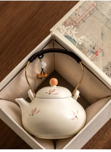 Detailed top view of ceramic teapot with golden handle in a traditional gift box