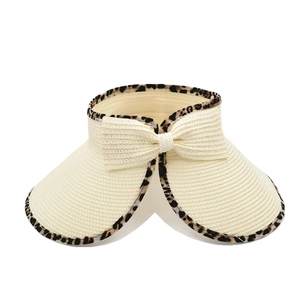 Detailed texture of beige paper straw sun hat with leopard print trim and bow