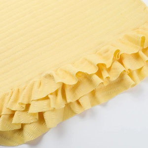 Detail shot of yellow knit fabric with vertical stripes and ruffled hemline textures