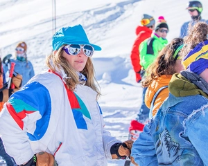 Dettaglio della giacca da sci retrò anni '80 con maschera bianca e accessori sportivi