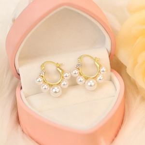 Detailed close-up of golden pearl tassel earrings in a pink velvet heart jewelry box