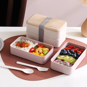 Pink double-layer bento box with wooden lid, elastic strap, and utensils for students