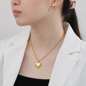 Close-up of elegant gold heart necklace and matching earrings worn by a model