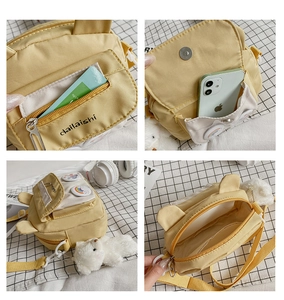 Detail view of yellow canvas crossbody bag featuring cute bear charm and multi-pocket storage
