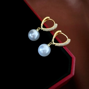 Macro shot of gold zircon hollow heart earrings with pearls in a luxury jewelry box