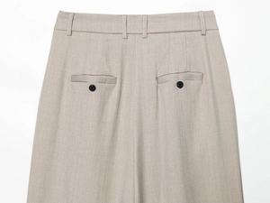 Detail of tailored trousers featuring back darts and dual welt pockets with black buttons