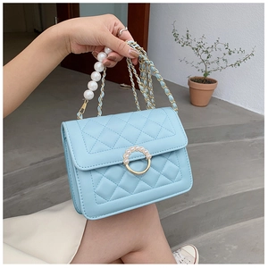 Detail of light blue quilted bag featuring elegant pearl handle and golden chain strap