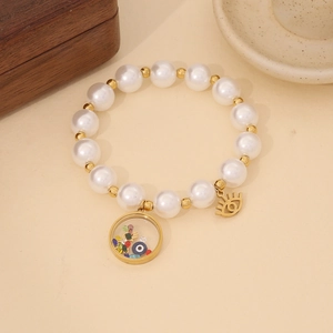 Detailed macro view of white faux pearls and golden evil eye charms on the bracelet