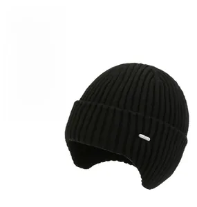 Detailed knit texture of black windproof winter hat with earflaps and metal logo label