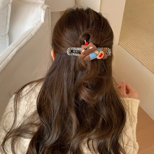 Detail of cute plush bear and black-white checkered fabric hair clip on wavy hair